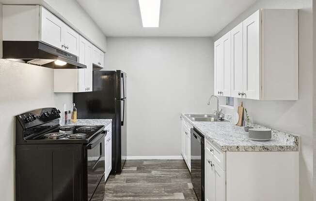 Model Kitchen with White Cabinets and Wood-Style Flooring at Tanque Verde Apartments located in Tucson, AZ.