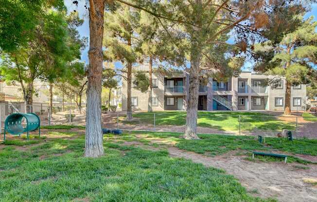A tree in a grassy area in front of apartment buildings.