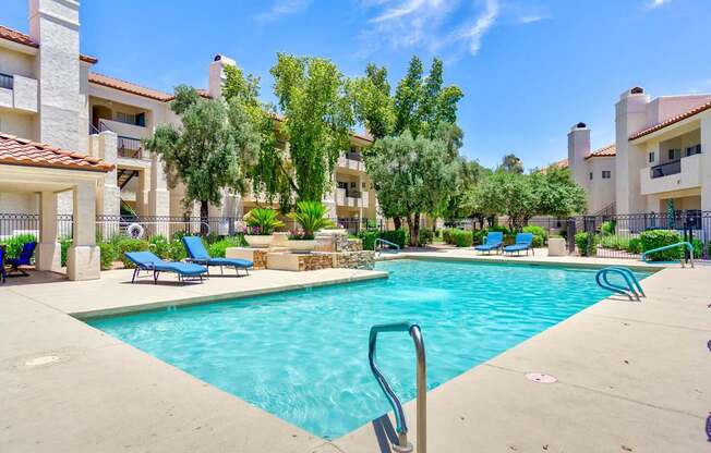 A swimming pool surrounded by a fence and chairs.