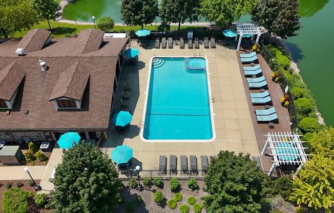 An aerial view of a swimming pool surrounded by sun loungers and umbrellas.