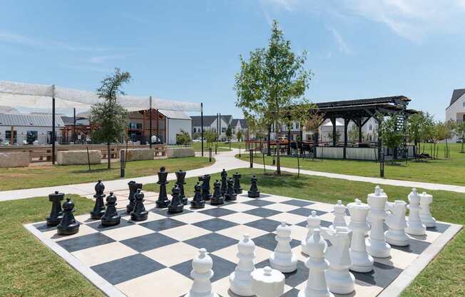 A giant chess set is set up on a grassy area.