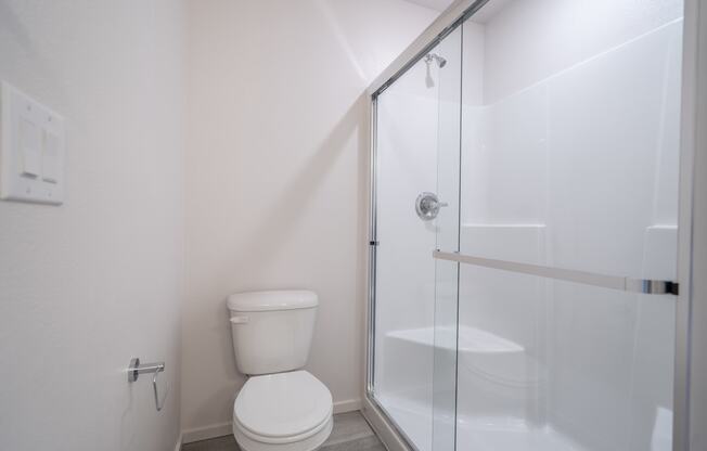 a bathroom with a toilet and a shower with a glass door