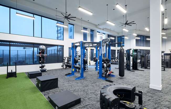 A gym with a variety of equipment including weights and a green artificial turf area.