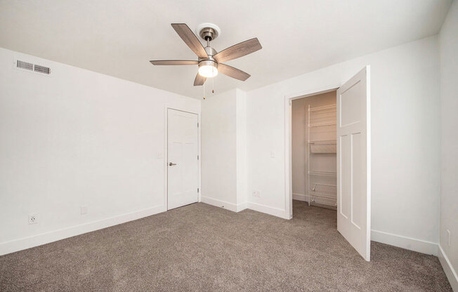 Carpeted bedroom with a ceiling fan and a closet