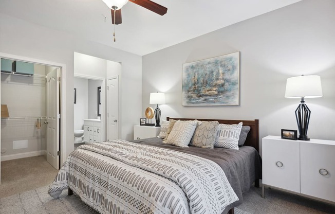 A bedroom with a bed, nightstand, and a painting on the wall.