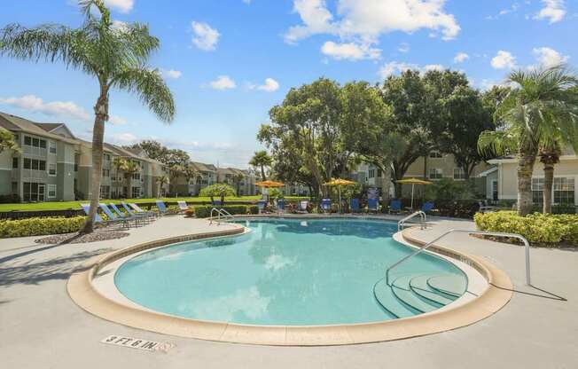 A large outdoor swimming pool surrounded by palm trees and lounge chairs.
