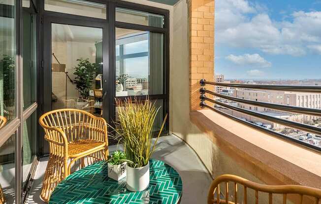 A balcony with a table and chairs overlooking a cityscape.