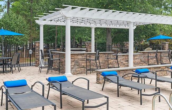 a patio with a bunch of chairs and umbrellas at Trails at Short Pump Apartments, Richmond, Virginia