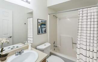 A white bathroom with a toilet, sink, and shower.