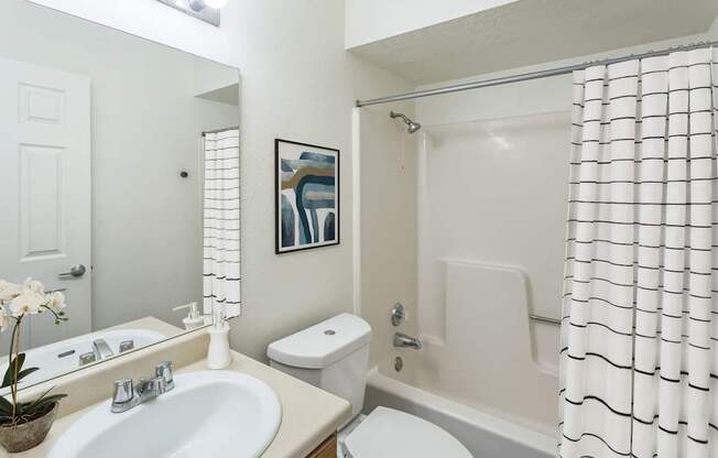 A white bathroom with a toilet, sink, and shower.