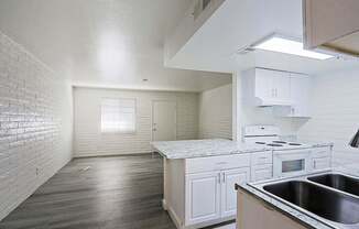 A kitchen with white cabinets and a stove top oven.