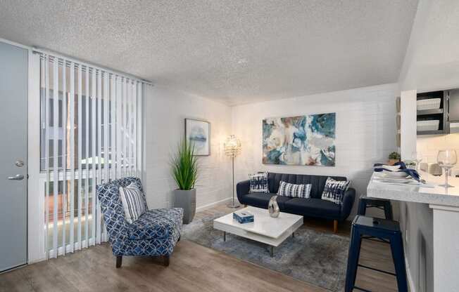 Dog-Friendly Apartments In Phoenix, AZ - Crosstown Phoenix - Large Living Room With White Brick Walls, Wood Inspired Flooring, A Breakfast Bar, And A Floor To Ceiling Window.