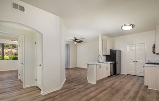 an open living room and kitchen with white walls and wood flooring