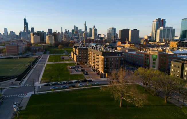 A cityscape with a mix of residential and commercial buildings, a park, and a road with cars.