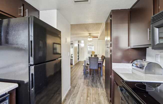 A kitchen with a black refrigerator and brown cabinets.