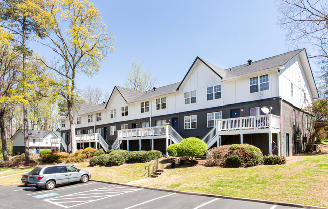 a large gray and white building with a car parked in front of it Barcelo at East Code Marietta, GA