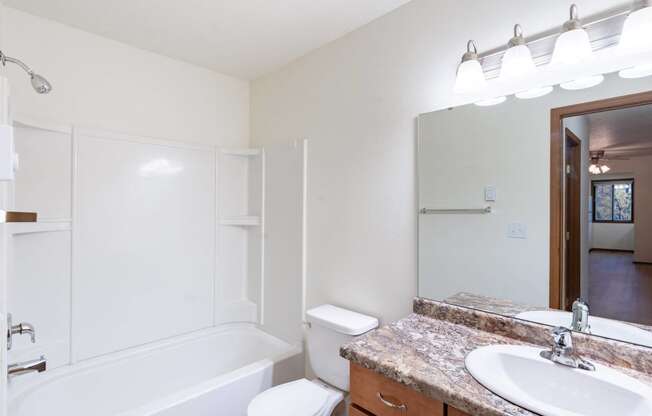 a bathroom with a sink and a toilet and a bath tub. Fargo, ND Flagstone Apartments