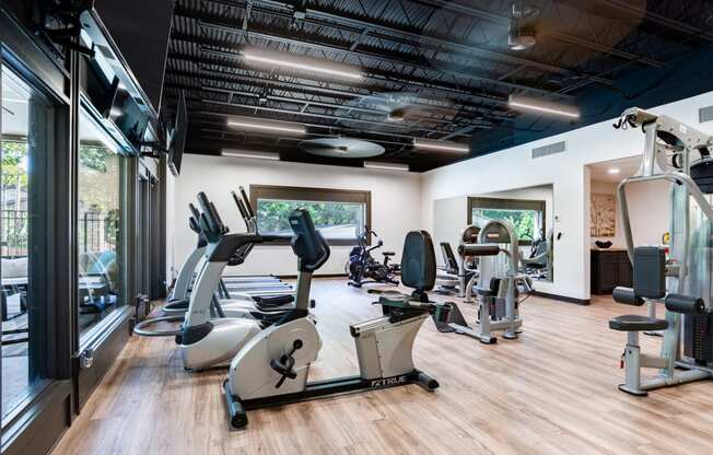 a gym with treadmills and other exercise equipment on a wooden floor