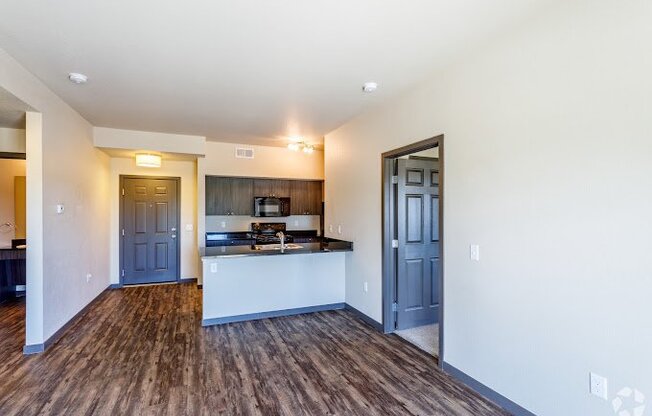 an empty living room with a kitchen and blue doors