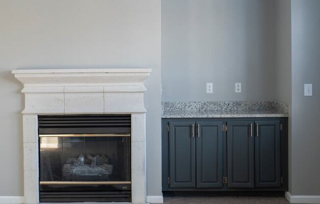 a fireplace with a mantel and a pair of cabinets next to it