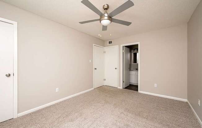 A room with a ceiling fan and carpeted floor.
