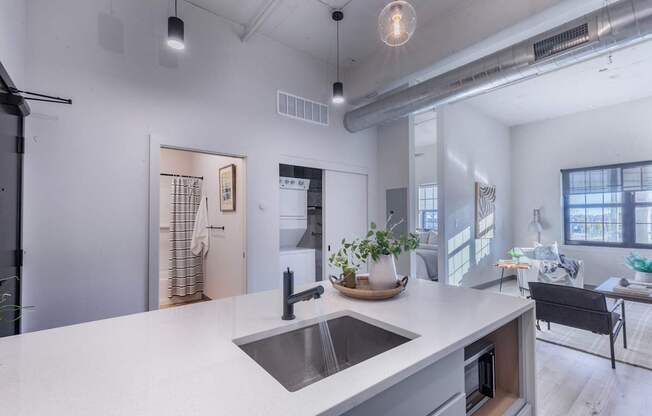 A modern kitchen with a white countertop and a stainless steel sink.