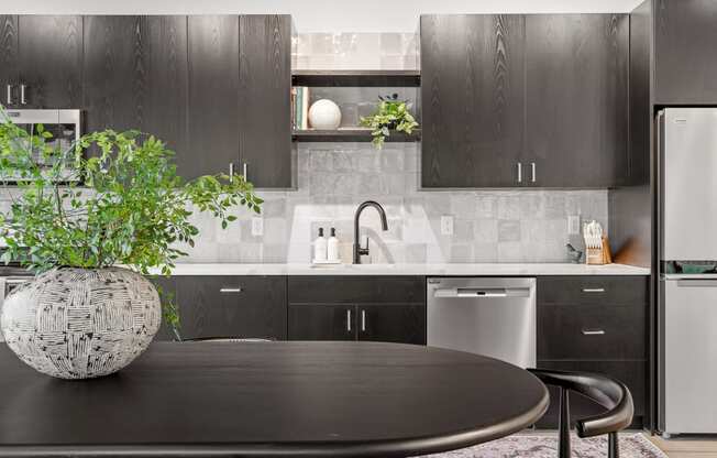 a kitchen with black cabinetry and a table with a potted plant