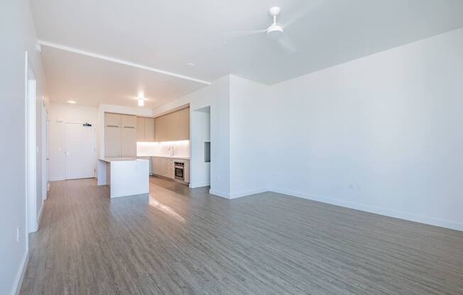 A room with a kitchen area and a dining table.