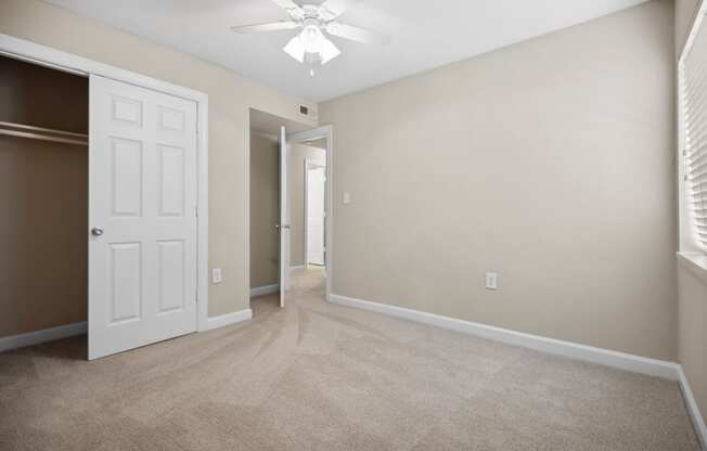 an empty living room with a white door and a ceiling fan
