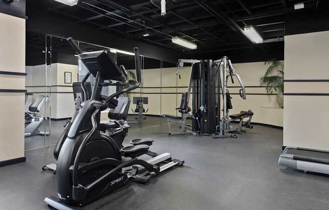 A gym with a variety of equipment including treadmills, weights, and exercise machines.