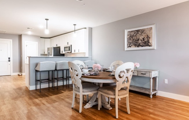a dining area with a table and chairs and a kitchen in the background