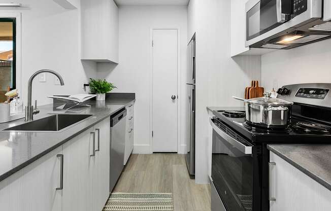 A modern kitchen with white cabinets and black countertops.