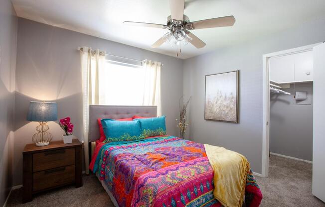 A bedroom with a bed, nightstand, and a ceiling fan.