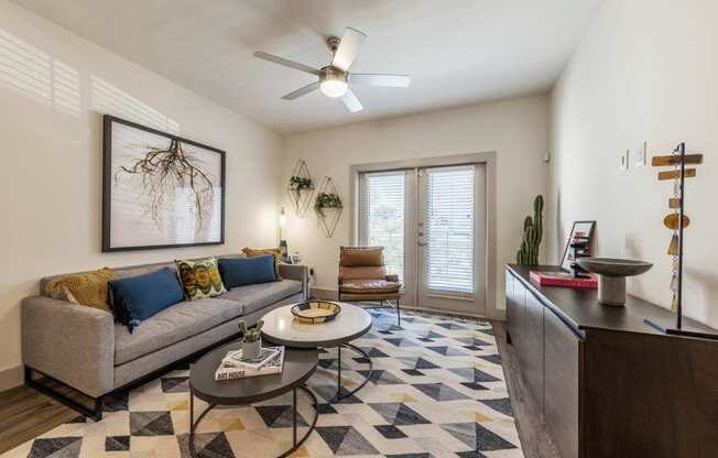 A living room with a grey couch, a coffee table, and a rug with a geometric pattern.