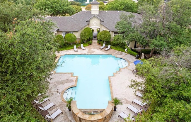 a swimming pool with lounge chairs and trees in the background