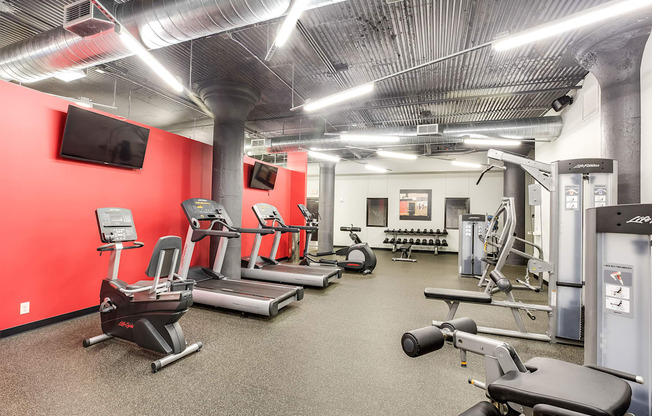A gym with a variety of equipment including treadmills, elliptical machines, and weight machines.