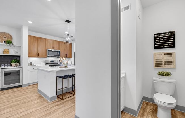 a white bathroom with a white toilet and a kitchen with wood floors at Meridian at CityPlace, Woodbury, 55125