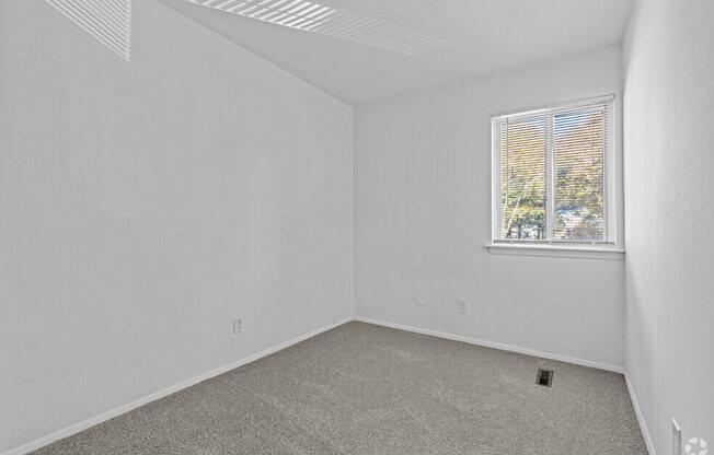 an empty room with white walls and a window