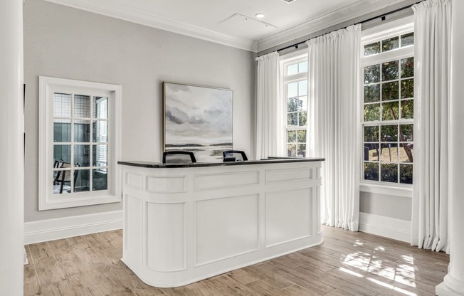 a white reception desk in a white room with windows