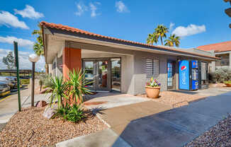 A Pepsi vending machine is outside a building with a red tile roof.