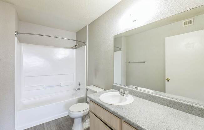 A white bathroom with a toilet, sink, and shower.