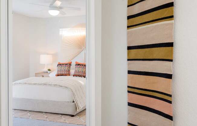 a bedroom with white walls and a white bed with a yellow and black blanket hanging on the