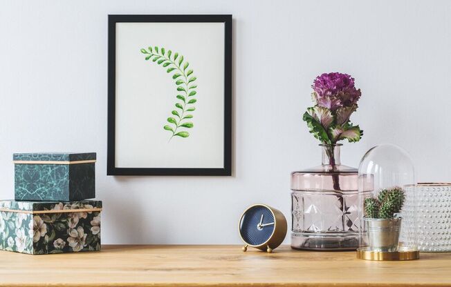 a picture frame on a table next to a clock and a vase of flowers