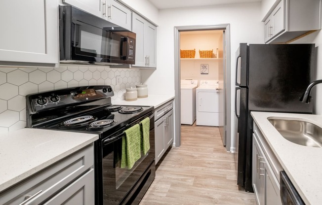 a kitchen with white cabinets and black appliances and a black refrigerator