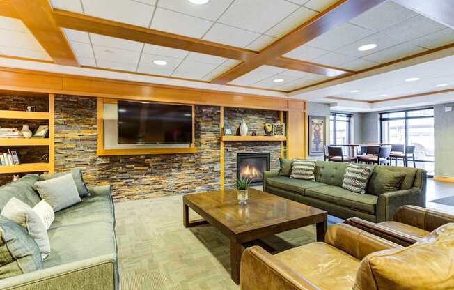 A living room with a stone fireplace and a flat screen TV mounted above it.