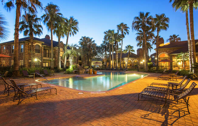 a swimming pool at night with palm trees