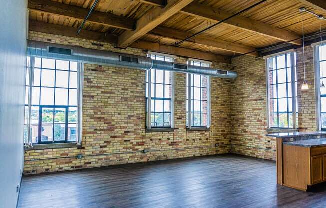 an empty room with a brick wall and large windows