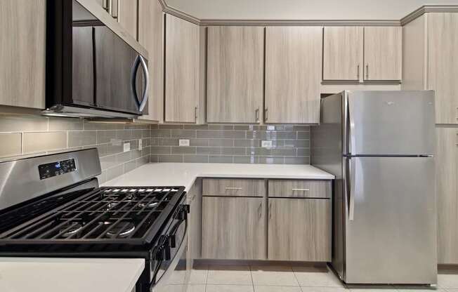 A modern kitchen with a stove, microwave, and refrigerator.