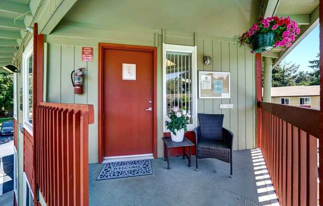 a front porch with a red door and two chairs