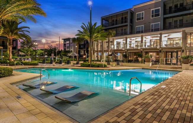 a swimming pool in front of a building with palm trees